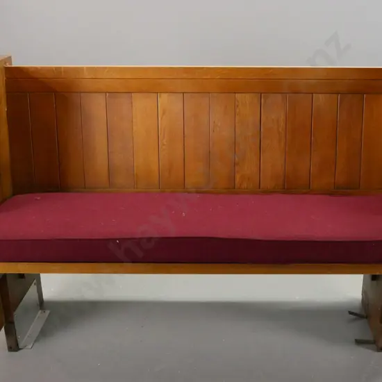 compact (3 seat?) oak church pew with maroon upholstered squab, metal floor mounting brackets. Some splintering at one