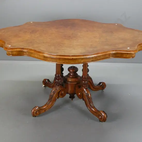 Victorian walnut centre table with serpentine shaped top on 4-point cathedral base on scrolling feet with porcelain