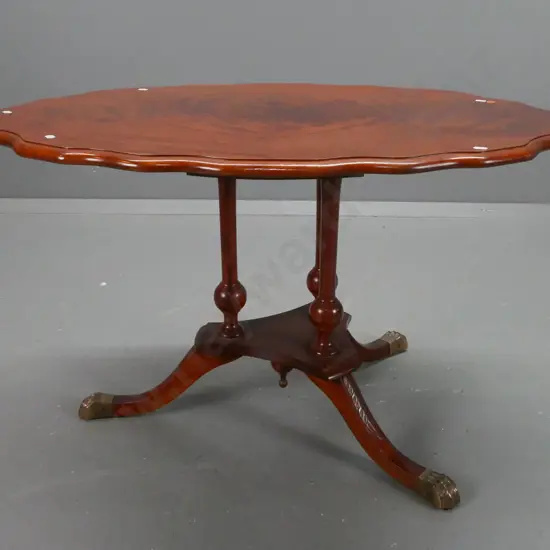 reproduction side table with figured mahogany top with shaped edge, 3-leg cathedral style platform base with brass lion