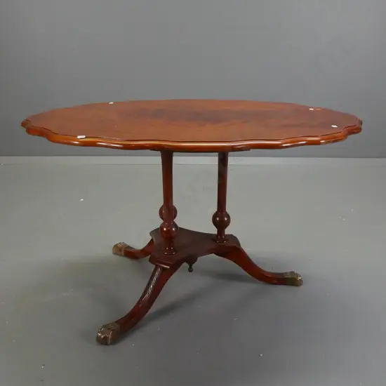 reproduction side table with figured mahogany top with shaped edge, 3-leg cathedral style platform base with brass lion