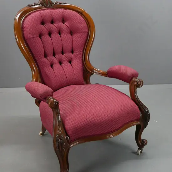 Victorian walnut open-armed armchair with shaped and carved arms, back and top crest, deep-button back, on