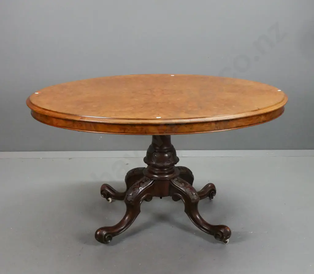 Victorian walnut oval loo table on column base w/ 4 carved scrolling legs, porcelain casters, working tilt top, slight Image 1++