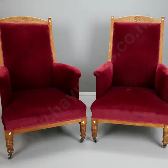 pair of late Victorian walnut armchairs w/ carved crest top rail, turned legs on metal casters, upholstered arms - arms