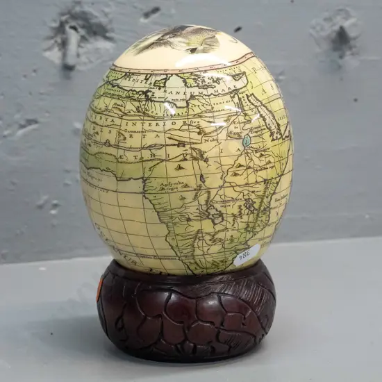 ostrich egg with transfer overlay on African animals and map on carved wood ring base with animal motifs. Combined H-200