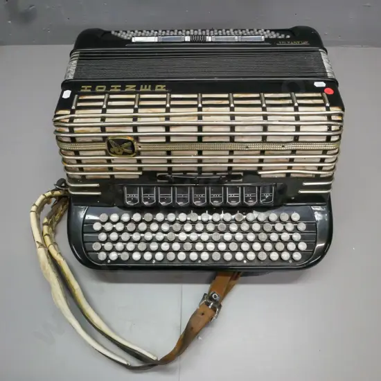 cased Hohner Atlanta 145 button accordion. Strap is worn & cracked, overall wear, discolouration to grille fabric,