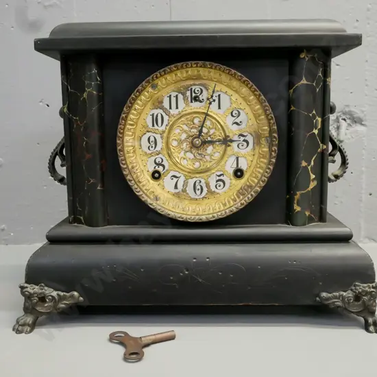 ebonised wooden mantel clock w/ marbled corners, applied scrolling cast handles, paw feet, gilded face. Gilbert Clock Co