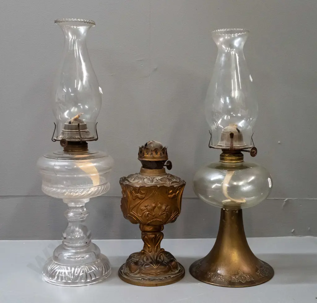 3 vintage kerosene lamps - brass base with nouveau style repeating pattern, clear glass tank & chimney, knob marked Image 1++