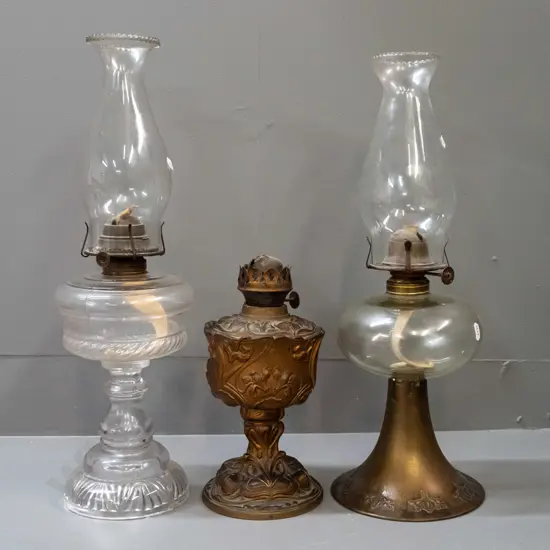 3 vintage kerosene lamps - brass base with nouveau style repeating pattern, clear glass tank & chimney, knob marked
