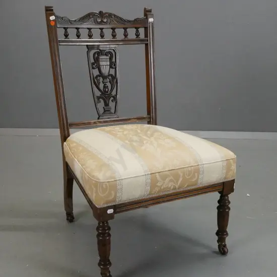Edwardian beech and walnut bedroom chair with carved back splat and top rail, on porcelain casters, striped upholstered
