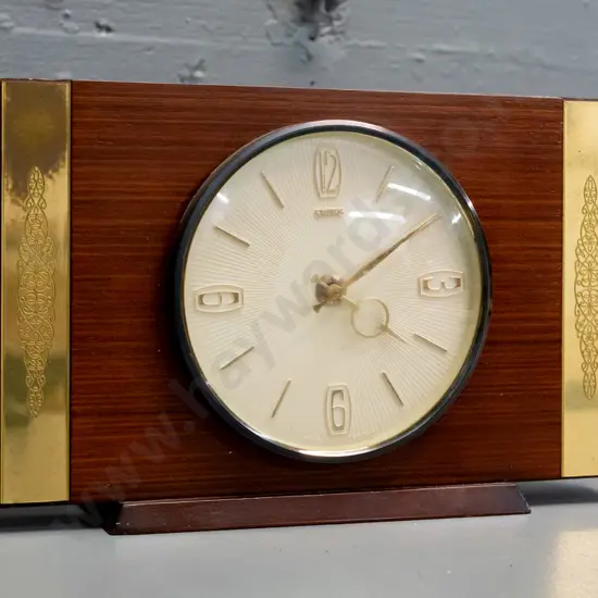 retro Smiths mantel clock with mahogany base, teak veneer and etched brass strapping, plastic-cased C battery movement.