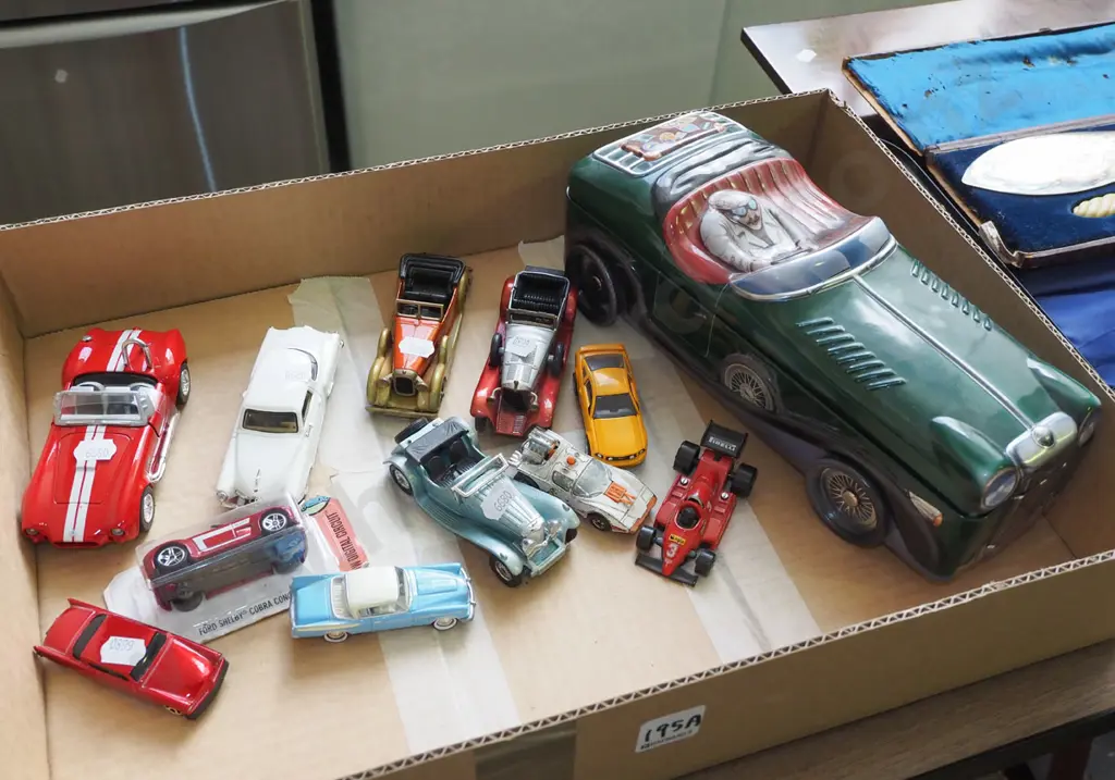 box of die-cast vehicles and a roadster shaped tin Image 1++
