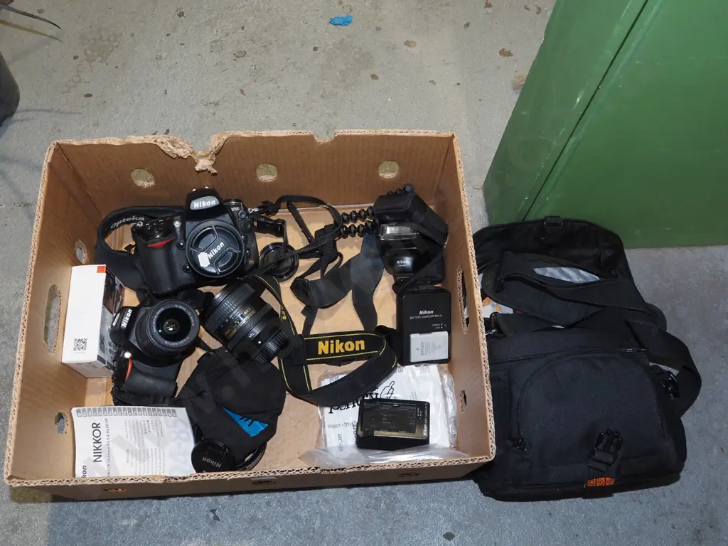 box; 2x Nikon digital SLR cameras, 3 lenses, flash, tripod etc. Image 1++