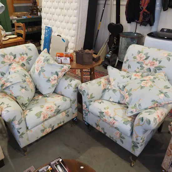 pair of magnolia floral armchairs with cushions and on brass casters