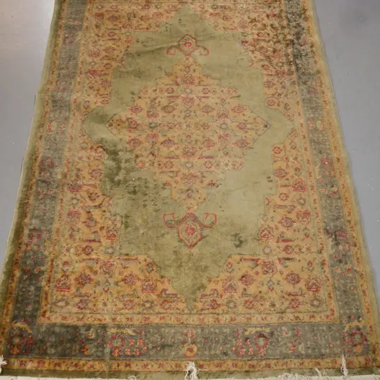Persian-style floor rug, green ground w/ red & camel geometric & floral borders. Some fading & wear.