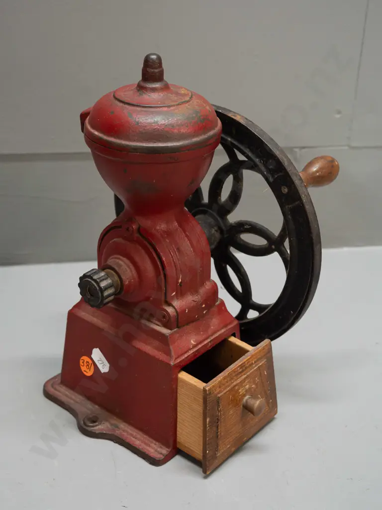 cast iron coffee mill with wooden knob on wheel, wooden wedge shaped drawer. Back of wheel marked Japan. H-245 W-180 Image 1++