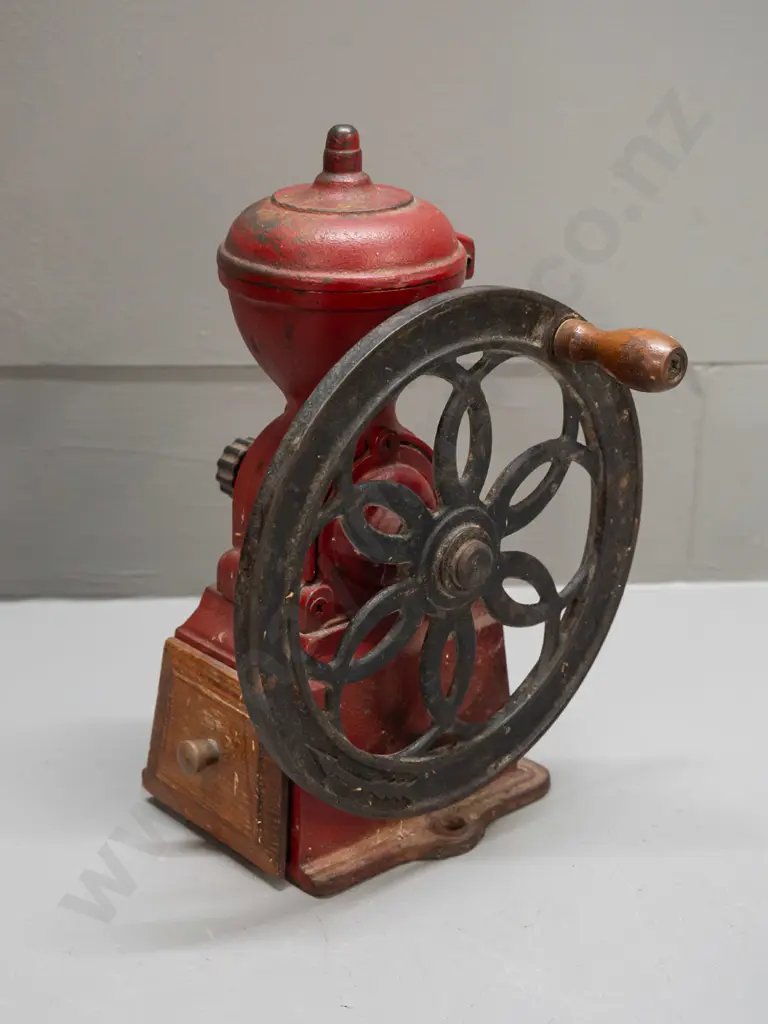 cast iron coffee mill with wooden knob on wheel, wooden wedge shaped drawer. Back of wheel marked Japan. H-245 W-180 Image 1++