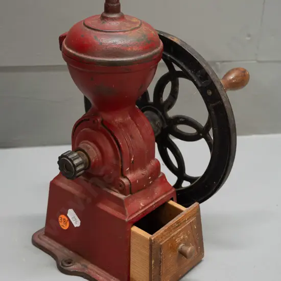 cast iron coffee mill with wooden knob on wheel, wooden wedge shaped drawer. Back of wheel marked Japan. H-245 W-180