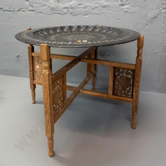 etched metal tole-ware tray on folding pierced and carved timber 4-legged base stamped Made in India. Some wear to black