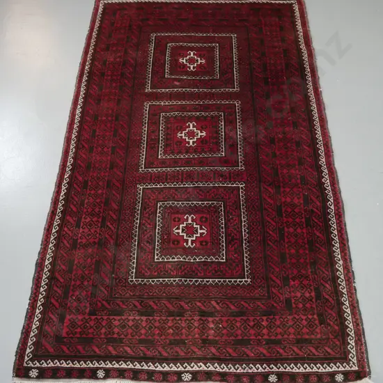 hand knotted woollen Persian style floor mat. Reds, browns, blacks and ivory. Wide borders, 3 geometric central panels.