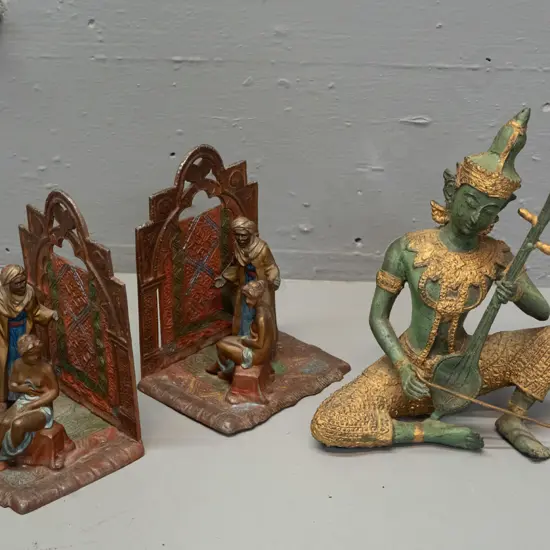 pair of Austrian cast metal book-ends with Arabian scenes and a Thai or Indonesian cast metal seated musician figure -