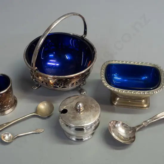 4 silver-plated salts & condiments with blue glass liners - and 3 spoons. Footed basket with handle H-110 L-100 marked
