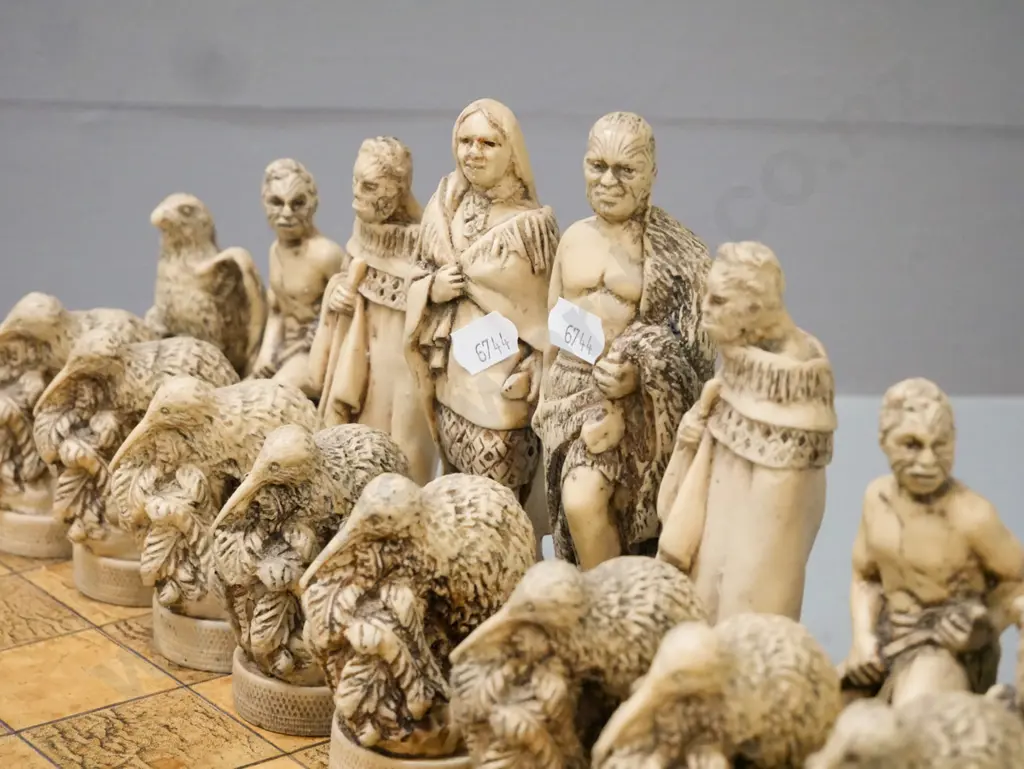 Māori-themed chess set w/ composite chess pieces & leather(?) laid on chessboard. Chessboard 380x380. Tallest Image 1++