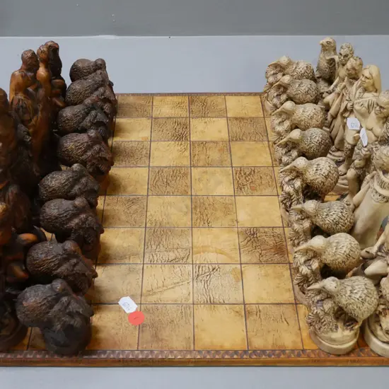 Māori-themed chess set w/ composite chess pieces & leather(?) laid on chessboard. Chessboard 380x380. Tallest