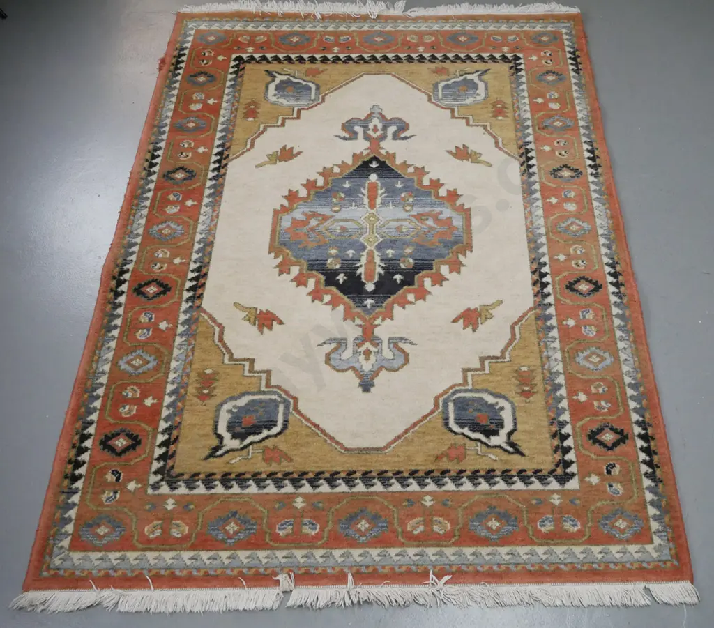 machine made woollen floor mat. Central geometric motif, ivories, blues, red. Overall fading and wear to edges. Image 1++