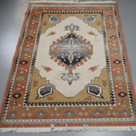 machine made woollen floor mat. Central geometric motif, ivories, blues, red. Overall fading and wear to edges.