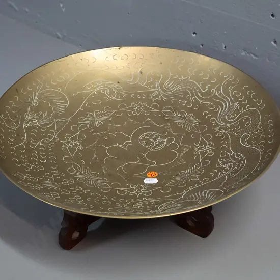 large brass bowl with etched dragon motifs, marked made in China on base, on 2 piece collapsible pierced wood stand,