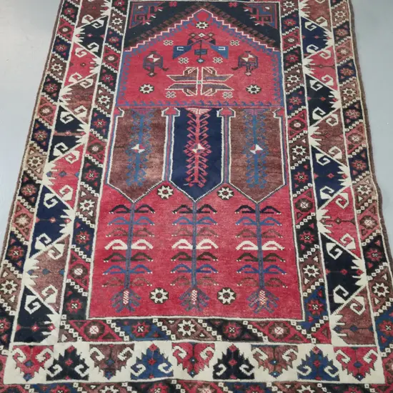 hand knotted woollen Persian style floor mat. Reds, ivories, blues. Geometric foliate decorations.
