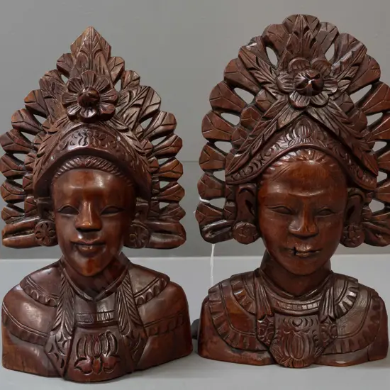 2 carved Indonesian hardwood busts with pierced edges - one with wall hanging eyelet in back - both with a few small