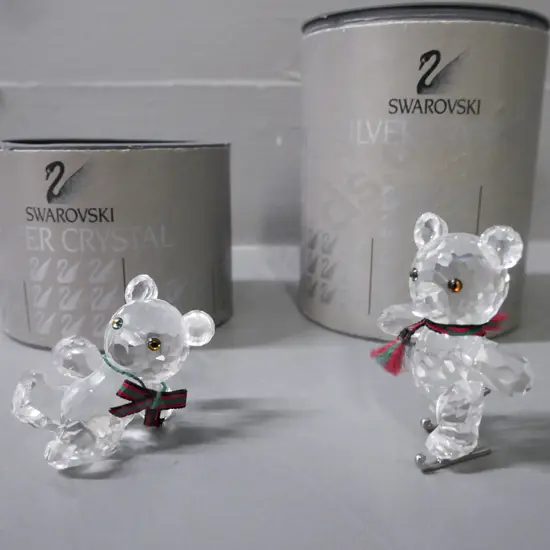 Swarovski 2x miniature teddy bear figurines, one skating, one lying down; w/ original packaging. H-50