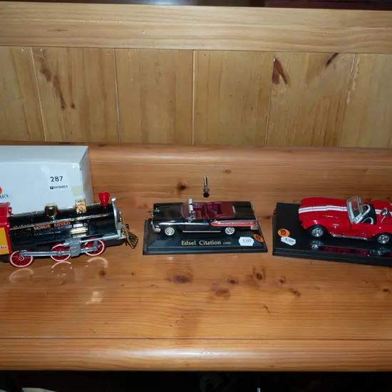 model train and 2x diecast model vehicles on plastic stands