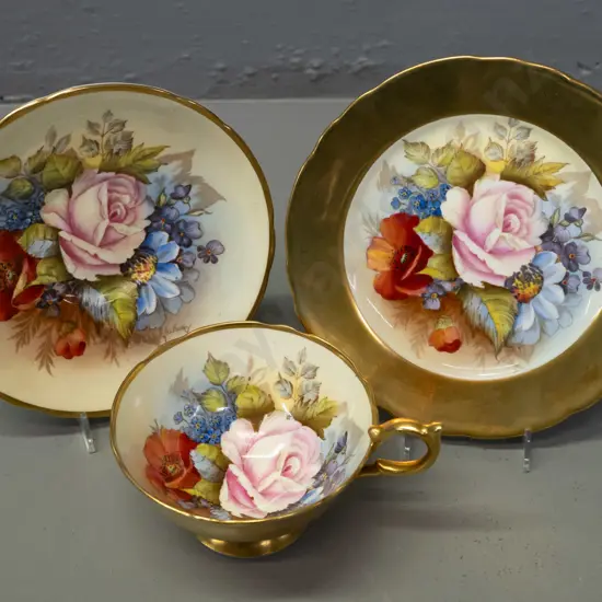 Aynsley hand painted floral and heavy gilt trio, each piece signed J. A. Bailey