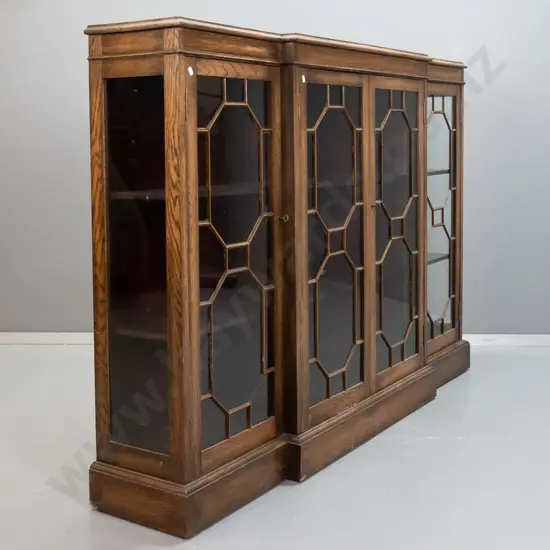 Edwardian oak break-front display cabinet with glazed sides, attached wooden astragals, 2 fixed shelves, red velvet back