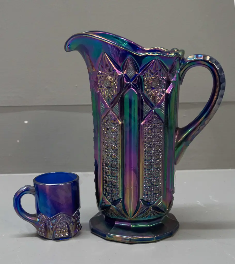 2 irridescent purple/blue carnival ware jugs - large one is H-210 W-180 handle to spout Image 1++