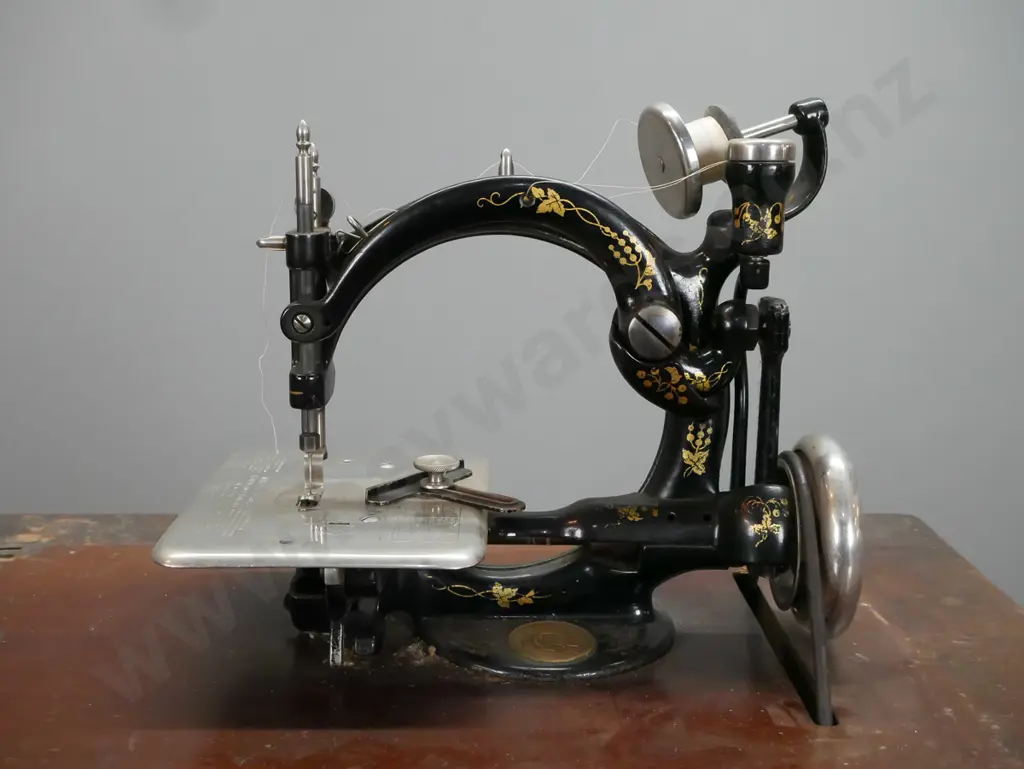 antique Wilcox and Gibbs NY treadle sewing machine on compact walnut and cast iron base with accessories in drawer, lift Image 1++