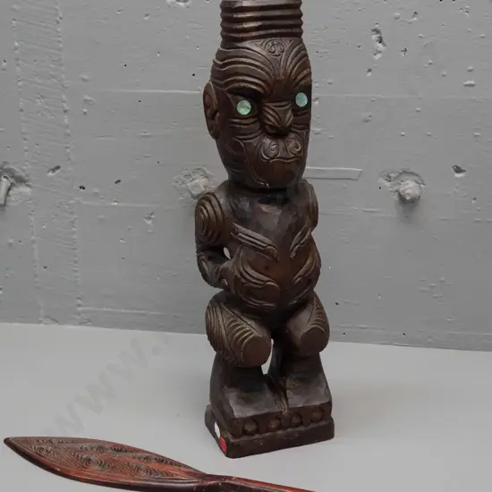 carved timber Maori standing figure with inset paua eyes - crack in base and a small carved timber decorative oar.