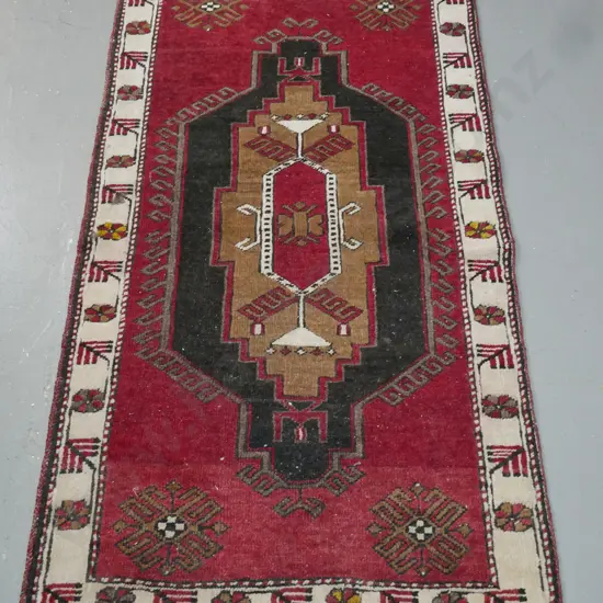 tribal style hand knotted wool floor rug with geometric red black brown and ivory pattern - some wear and staining, red