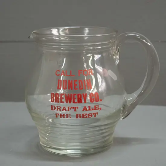 clear glass jug with ribbed base marked "Call for Dunedin Brewery Company Draft Ale - The Best" Minor wear to lettering