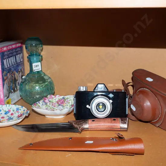 shelf; floral dishes, DVDs, decanter, film camera, knife with sheath