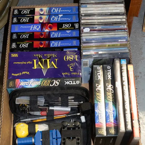 box; unused VHS tapes, DVDs, CDs, watchmaker's repair kit