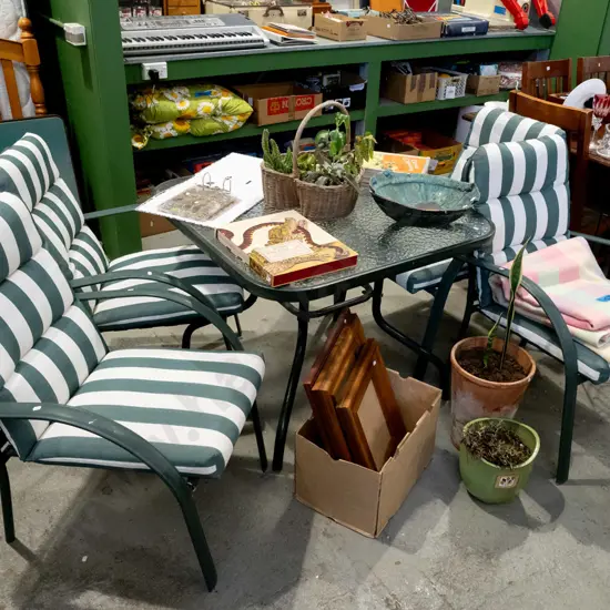 glass top outdoor table with 4 matching chairs and green striped cushions