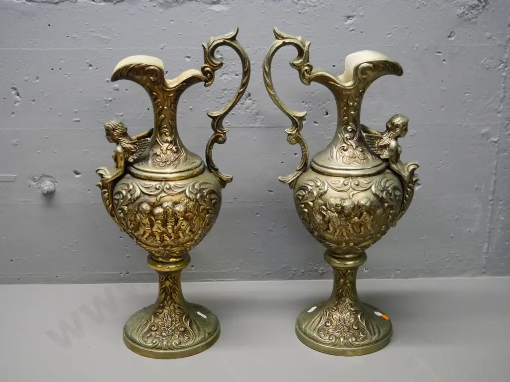 pair of ornate brass finish cast metal ewer jugs with cupid and angel motifs H-500 W-230 at handle Image 1++