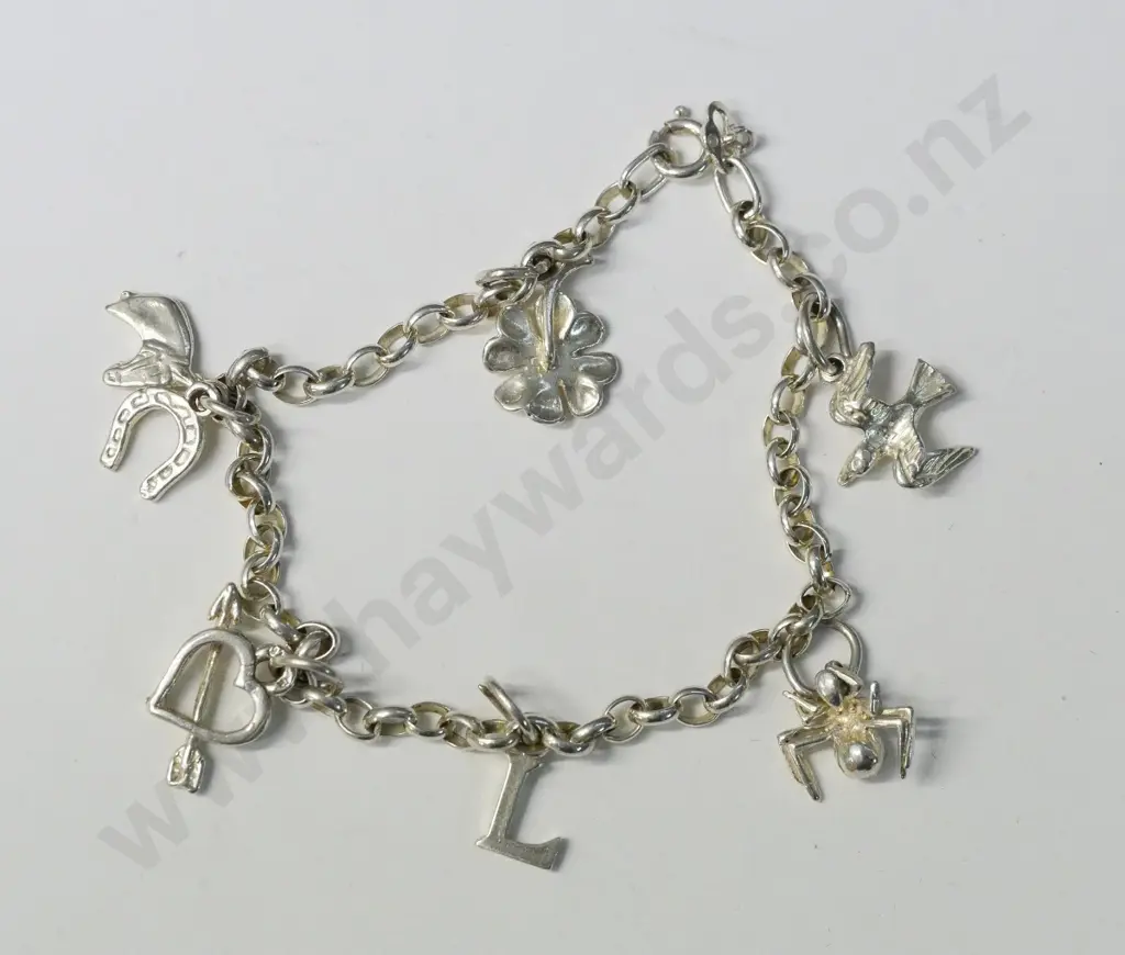 silver charm bracelet has 7 charms flower,bird,horse, horse shoe,spider,heart,letter L Image 1++