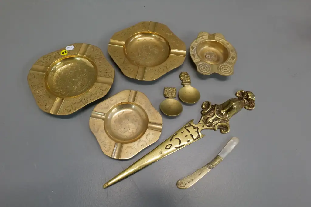 assorted brass items - etched ashtrays, heavy letter opener, 2 tea scoops - & a plated mother of pearl butter knife Image 1++