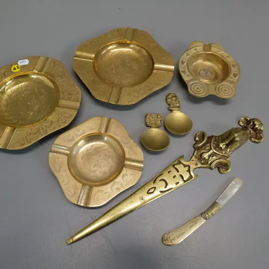assorted brass items - etched ashtrays, heavy letter opener, 2 tea scoops - & a plated mother of pearl butter knife