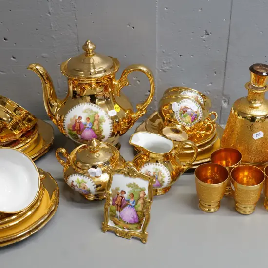 gilt china: German romance scene 21-piece tea set, 7-piece decanter set (fault to rim) and a Limoges plaque
