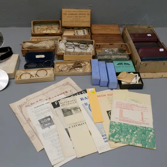 collection of vintage optical items including eyeglass frames and parts, boxed and loose lenses, glass cases, etc.
